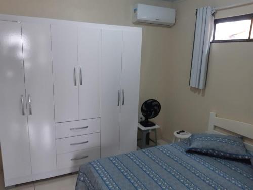 um quarto com uma cama, armários brancos e uma janela. em Pousada Residencial Caroa em Florianópolis