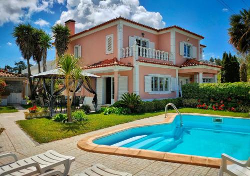 a villa with a swimming pool in front of a house at Villa Shardana B&B in Sesimbra