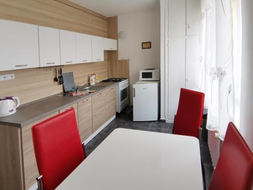 a kitchen with white cabinets and red chairs in it at byt s balkonem in Žatec