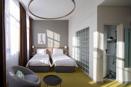 a hotel room with two beds and a chair at Four Rooms City in Kharkiv