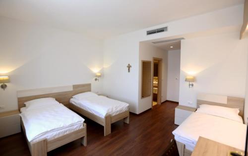 two beds in a room with wooden floors at Hotel Quercus in Međugorje