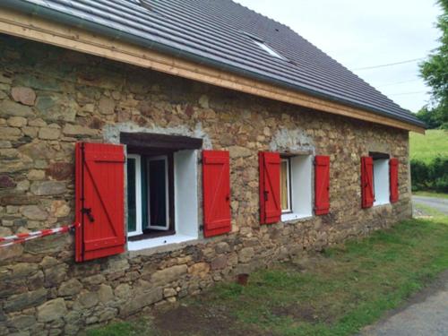a stone building with red shutters on it at Appartement charmant Orgnac-sur-Vézère avec jardin et parking in Orgnac-sur-Vézère