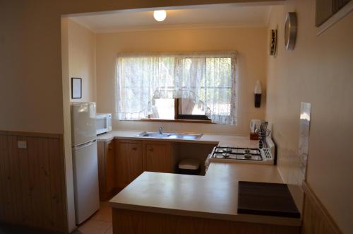 a kitchen with a white refrigerator and a sink at Mountain View Motor Inn & Holiday Lodges in Halls Gap
