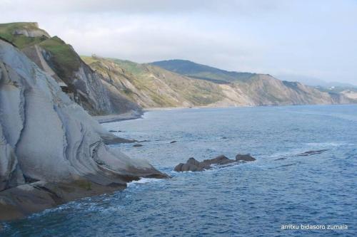 a large body of water with rocks in the ocean at Itzurun, Zumaia, te encantara! in Zumaia