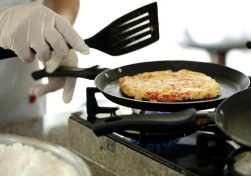 Eine Person brät eine Pizza in einer Pfanne auf dem Herd in der Unterkunft San Marco Hotel Brasília in Brasilia