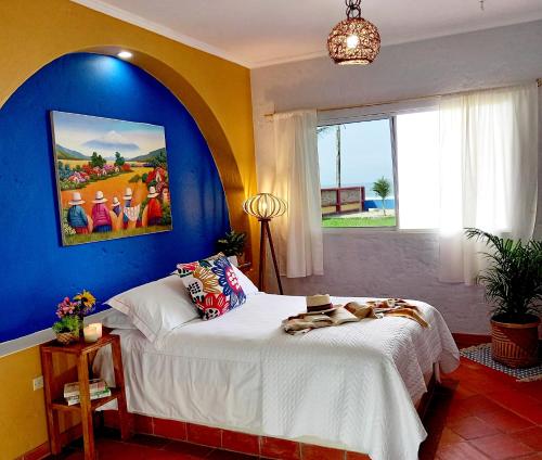 1 dormitorio con 1 cama grande y pared azul en Casa Amarilla, en Puerto Cayo