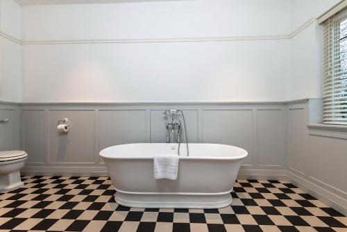 a white bath tub in a bathroom with a checkered floor at Edgbaston Park Hotel Birmingham in Birmingham