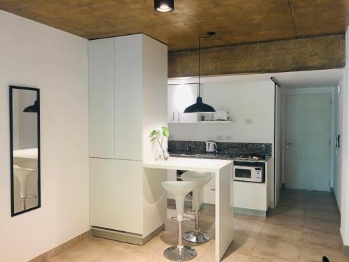 uma cozinha com armários brancos, uma mesa branca e um banco em Studio II em Belén de Escobar