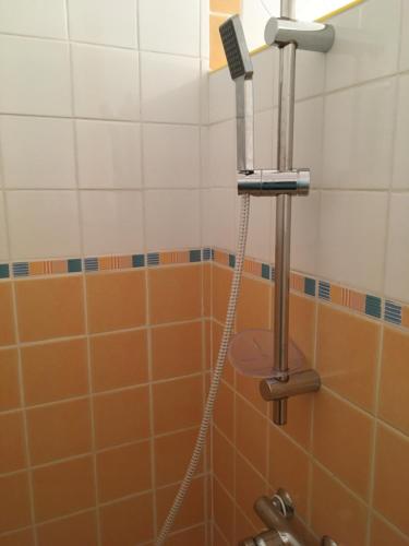 La salle de bains est pourvue d'une douche et de carrelage orange et blanc. dans l'établissement Studio meublé 28m2 vue côté Balaruc centre et massif de la Gardiole, à Balaruc-les-Bains