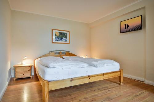 BraderupにあるBraderuper Heideのベッドルーム(木製ベッド1台、ナイトスタンド付)