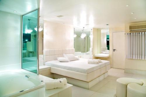 a white bathroom with a bed and a bath tub at BAMBINA HOTEL -Adultos Somente in Rio de Janeiro