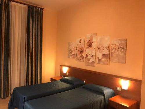 a hotel room with two beds and paintings on the wall at Hotel Paradiso in Milan