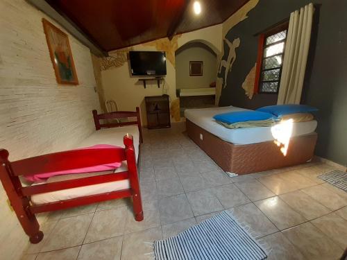 a bedroom with two beds and a tv in a room at Pousada Ritmo Natureza in São Thomé das Letras