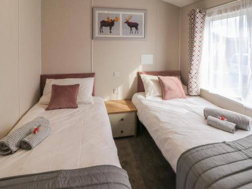 two twin beds in a room with a window at Sea Holly Lodge in Saltburn-by-the-Sea