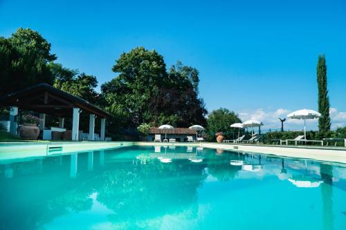 une grande piscine d'eau bleue avec des tables et des parasols dans l'établissement Agriturismo Relais "il Bricco", à Nizza Monferrato