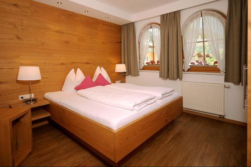 1 dormitorio con 1 cama con sábanas blancas y almohadas rojas en Landhaus Michael, en Mayrhofen