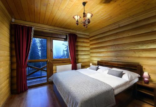 a bedroom with a bed and a large window at High Tatras Chalet in Štrbské Pleso