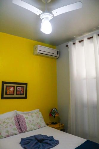 a bedroom with a bed and a window with a fan at Pousada Do Suiá in Arraial do Cabo