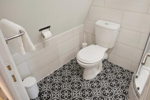 a bathroom with a toilet and a black and white tile floor at Villa Noellet - Clermont Ferrand in Aubière