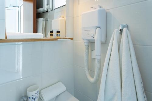 La salle de bains est pourvue de toilettes blanches et d'un porte-serviettes. dans l'établissement Mediterraneo Apartments, à Archangelos