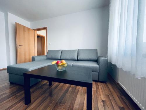 uma sala de estar com um sofá e uma mesa com uma taça de fruta em Ferienwohnungen Hecker em Bad Gögging