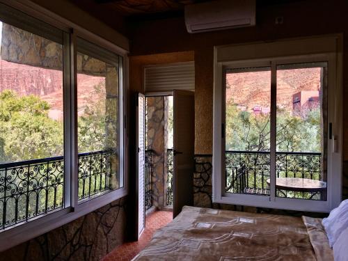 a bedroom with two windows and a bed with a view at La Petite Gorge, Hôtel & Restaurant Todra Gorge in Tinerhir