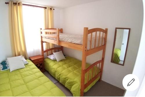 1 dormitorio con 2 literas y espejo en Cerquita del Mar Departamento Entero en La Serena