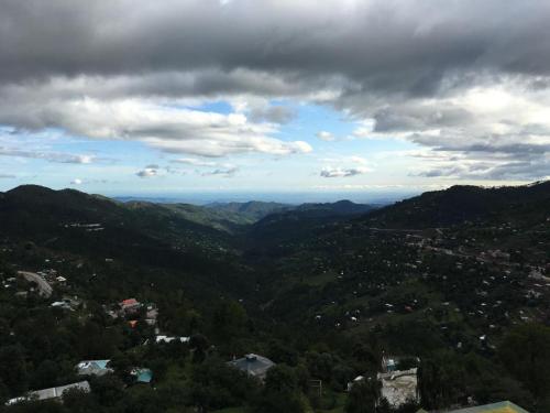 a view of a mountain valley under a cloudy sky at Aloche Apartments in Murree