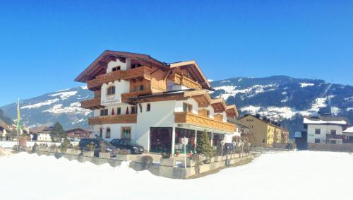 a building in the snow with mountains in the background at Hotel Restaurant Rosengarten in Zell am Ziller