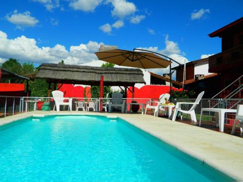 a swimming pool with a table and chairs and an umbrella at La Posada Del Poeta in Mina Clavero