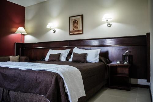 a bedroom with a large bed with a wooden headboard at Hotel Ciudad in Santiago del Estero