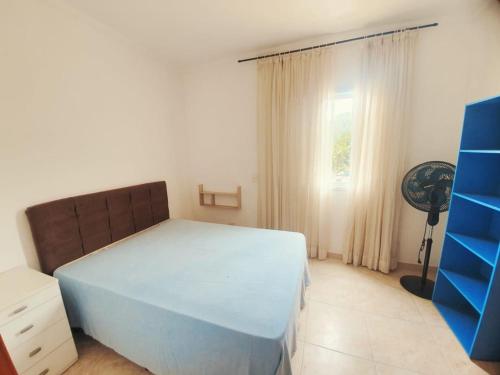 Un dormitorio con una cama azul y una ventana en Lindo apto com 3 quartos, apenas 1 quadra da praia das Toninhas, en Ubatuba