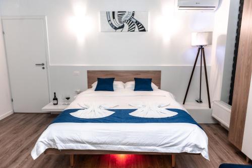 um quarto com uma grande cama branca com almofadas azuis em Puzzle Apartaments&Studios em Craiova