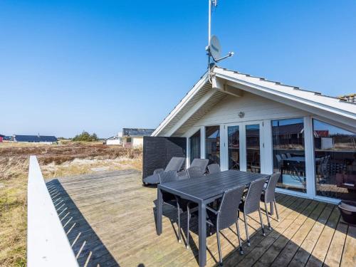 una terraza con una mesa negra y sillas. en Holiday home Hvide Sande LXX, en Bjerregård