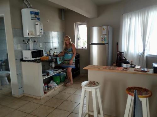 a woman standing in a kitchen preparing food at Luminoso y bello departamento en Carlos Paz in Villa Carlos Paz