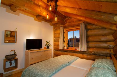 una camera da letto in una baita di tronchi con letto e TV di Berg & Sonne a Seeboden