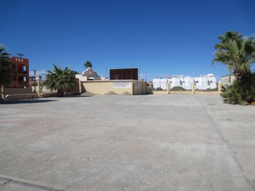a large empty parking lot with palm trees and buildings at Hotel Plaza Peñasco in Puerto Peñasco