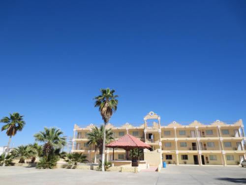 a large hotel with palm trees in front of it at Hotel Plaza Peñasco in Puerto Peñasco