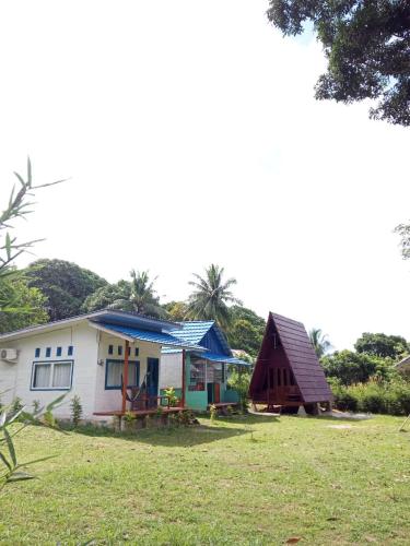 a small white house with a blue roof at Tanjong Tinggi Cottage in Sijuk