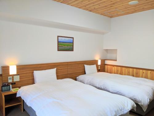 2 łóżka w pokoju hotelowym z białą pościelą w obiekcie Dormy Inn Premium Sapporo w mieście Sapporo