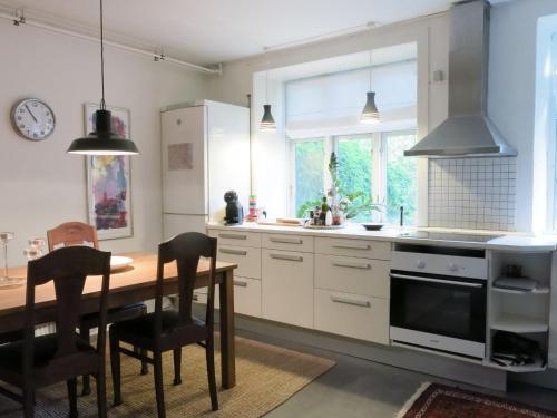 una cocina con armarios blancos y una mesa de madera con sillas. en ApartmentInCopenhagen Apartment 1316, en Copenhague