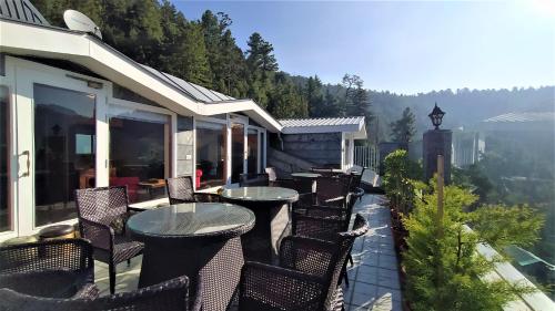 a patio with tables and chairs on a balcony at The Retreat Mashobra, Shimla in Shimla