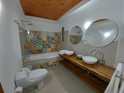 a bathroom with two sinks and two mirrors at La Alhambra Hotel Boutique in Villa de Leyva
