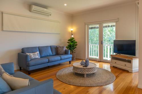 a living room with a blue couch and a tv at Views On Montpellier in Healesville