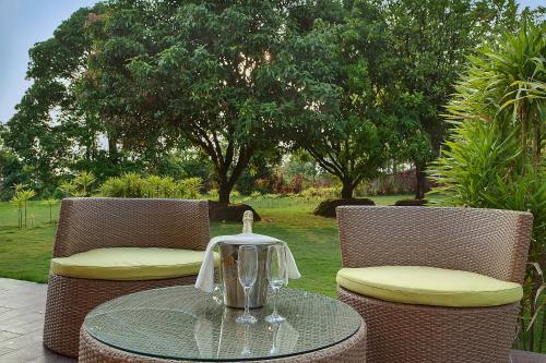 a glass table and chairs with a tea kettle on it at Sinclairs Retreat Dooars, Chalsa in Chālsa
