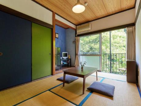 un soggiorno con tavolo e parete verde di Otsu Nature Garden ad Akiruno
