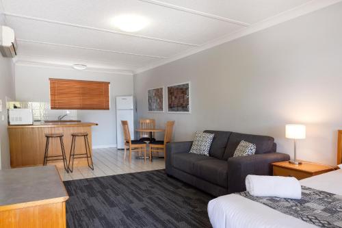 a living room with a couch and a kitchen at Country Motel Ipswich in Ipswich