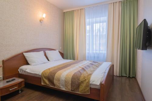 トムスクにあるApart Petrovskie on Tverskaya 105のベッドと窓が備わるホテルルーム
