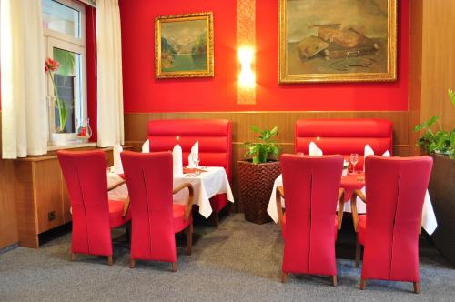 a restaurant with red chairs and tables in a room at Hotel-Restaurant Weinberg in Artern