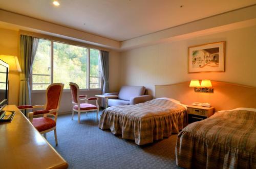 a hotel room with two beds and a chair at Jozankei Manseikaku Hotel Milione in Jozankei